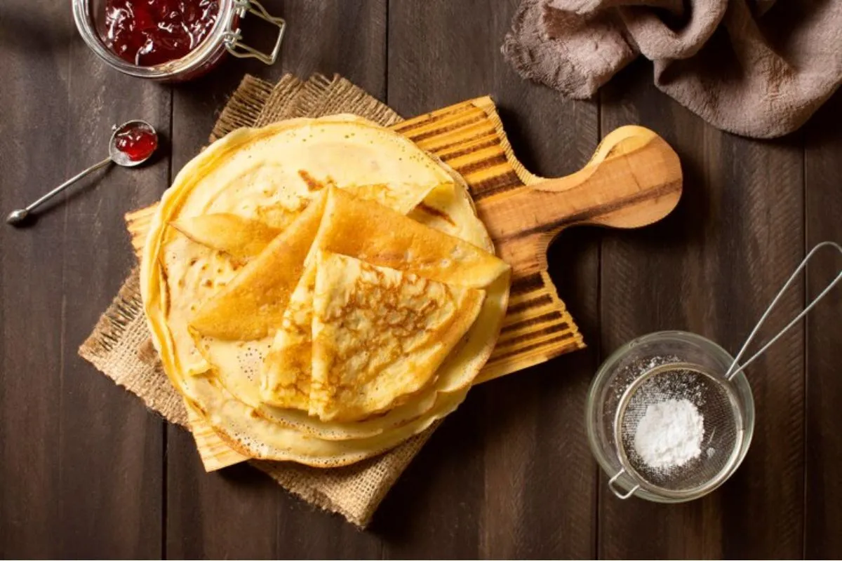 Massa de crepe pronta e servida sobre tábua de frios e em cima de mesa na cor preta