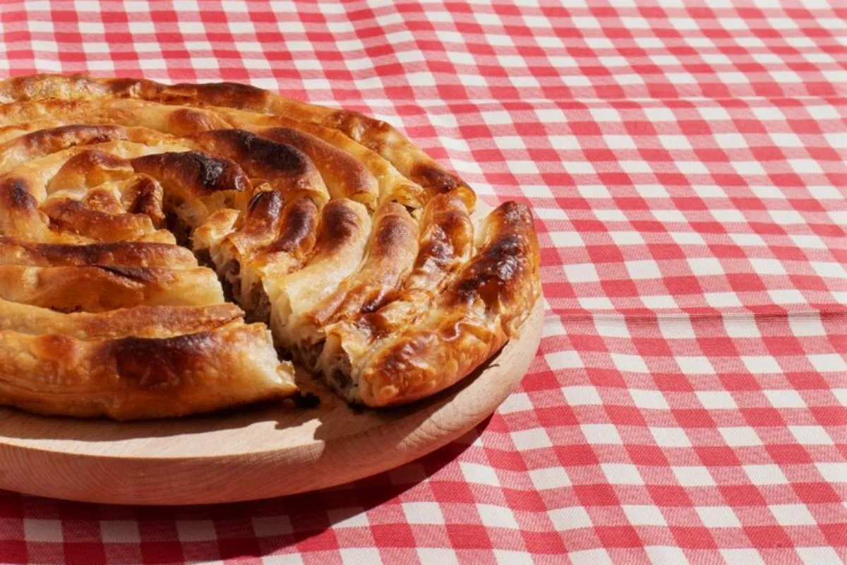 Torta de salsicha sobre mesa decorada com toalha vermelha